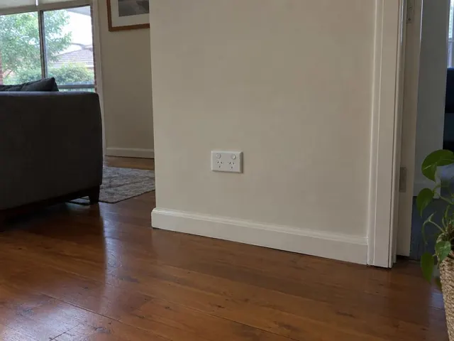 White double power point on a painted wall above timber floorboards in a living room in Bella Vista